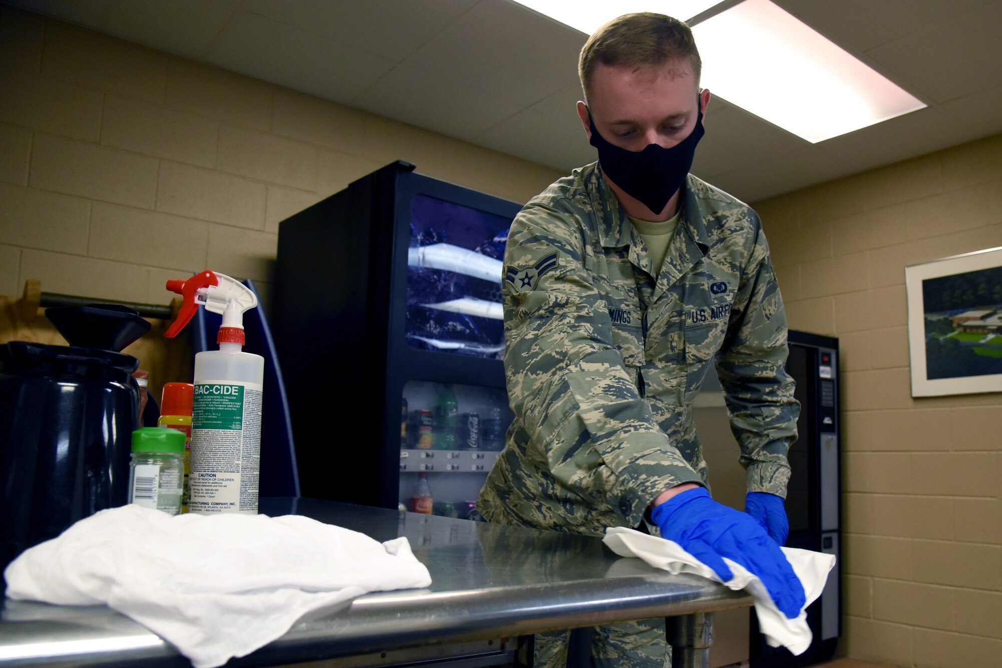 U.S. Air Force Airman 1st Class Garrett Cummings a COVID-19 infection control team volunteer disinfects frequently used areas on the installation at the 117th Air Control Squadron at Hunter Army Airfield June 16, 2020.  The base infection control teams minimize the potential spread of COVID-19 for unit members by disinfecting common areas and workplaces as a precautionary measure. (U.S. Air National Guard photo by Staff Sgt. Jamila Haven)