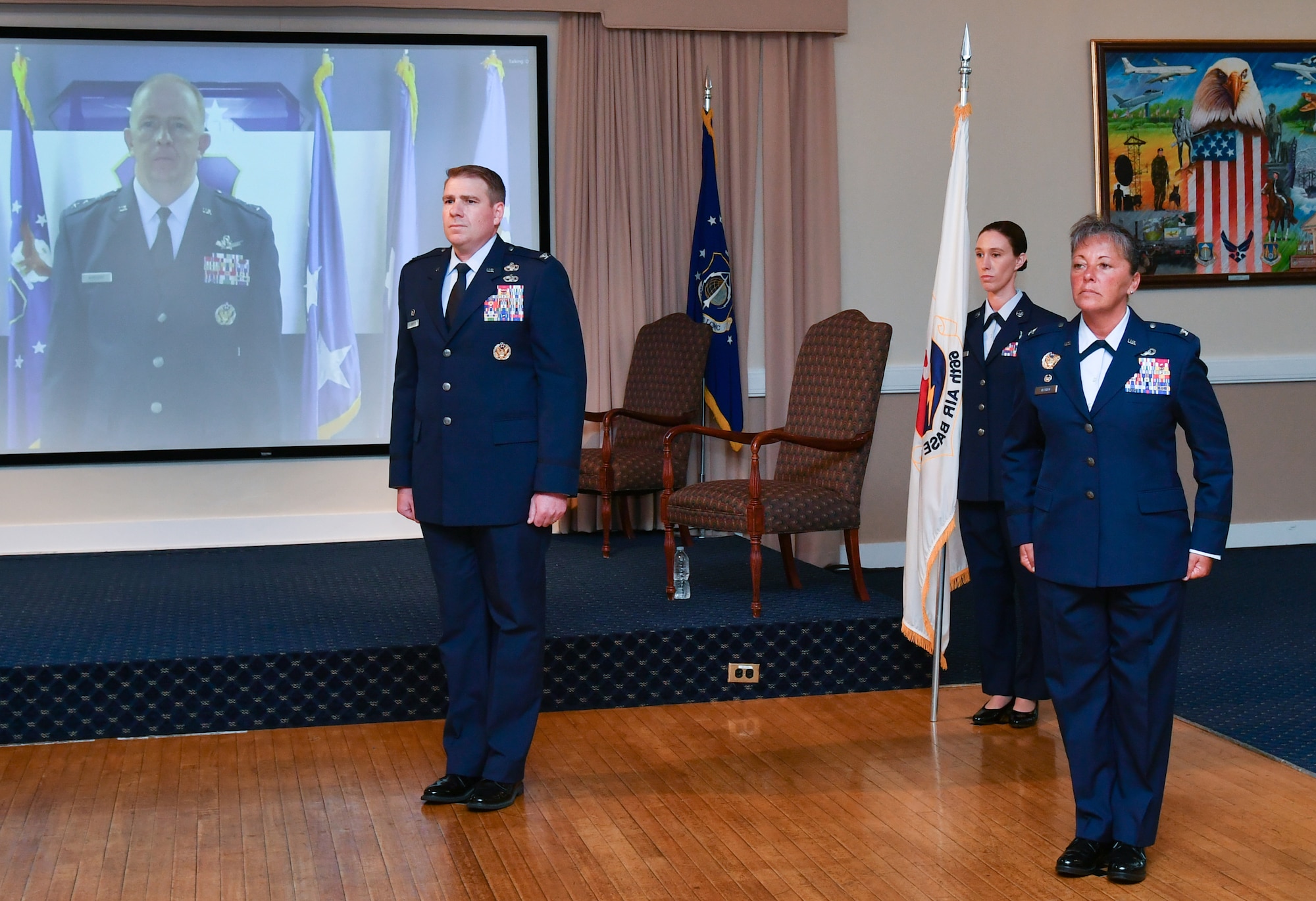 Col. Katrina Stephens stands at attention next to Col. Chad Ellsworth during the 66th Air Base Group change of command ceremony at Hanscom Air Force Base, Mass., while Lt. Gen. Robert McMurry, Air Force Life Cycle Management Center commander, looks on via teleconference. Stephens is taking command of the group after serving as the vice commander of the 78th Air Base Wing at Robins AFB, Ga., and is returning to Hanscom, where she served early in her Air Force career. (U.S. Air Force photo by Linda LaBonte Britt)