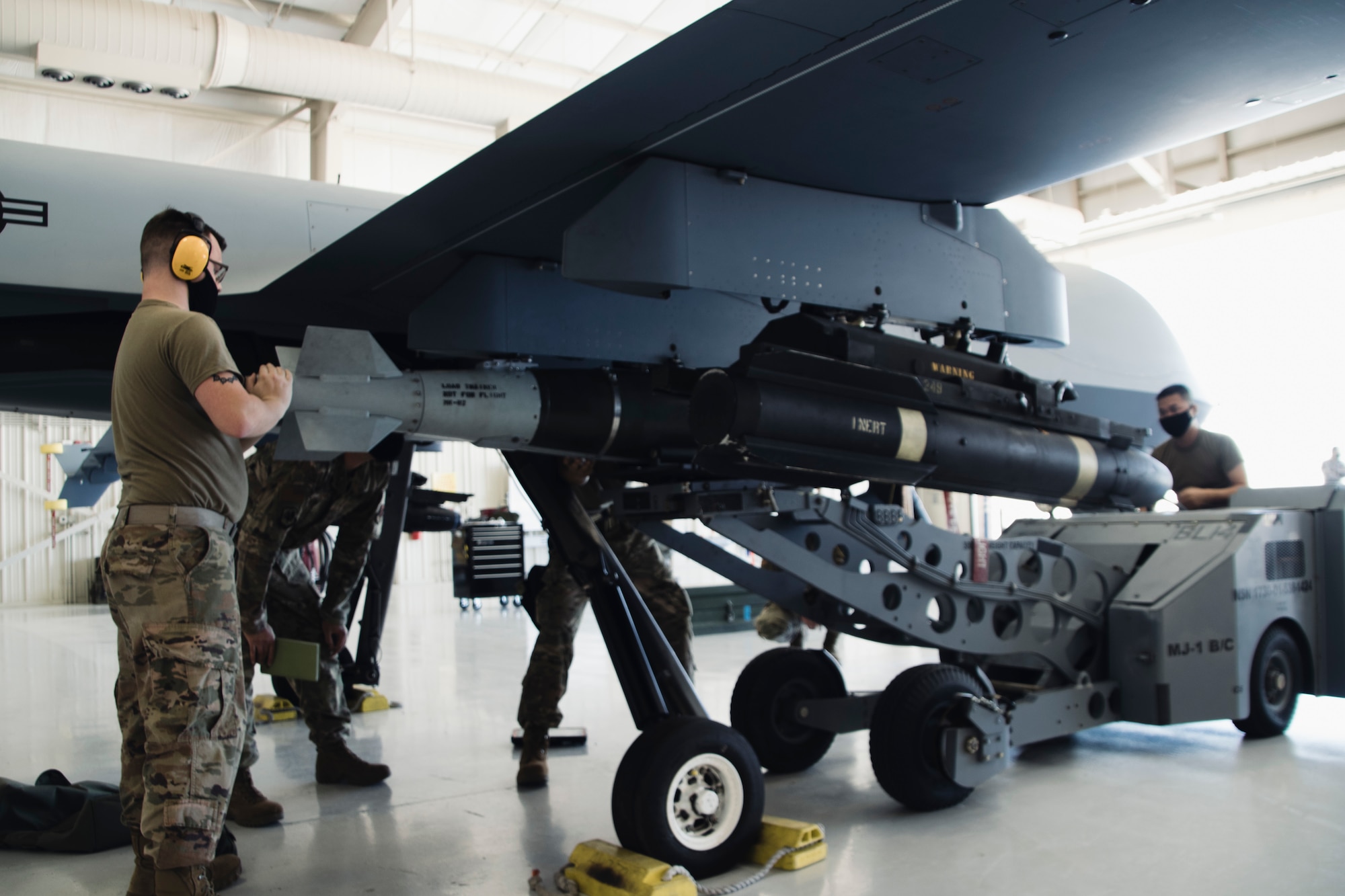 Airmen wearing facemasks compete to arm an MQ-9 Reaper during a quarterly load crew competition.