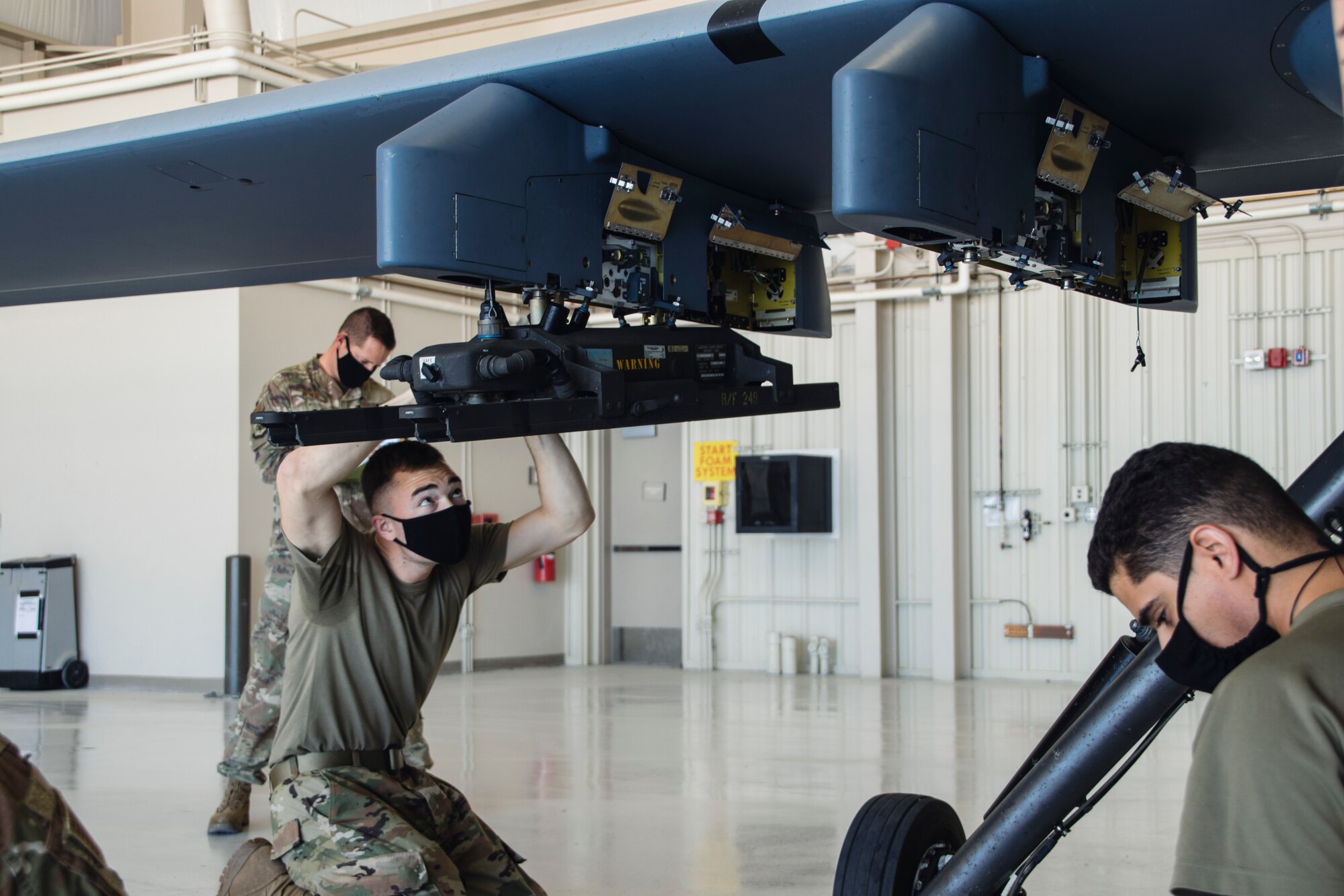 Airmen wearing facemasks compete to arm an MQ-9 Reaper during a quarterly load crew competition.