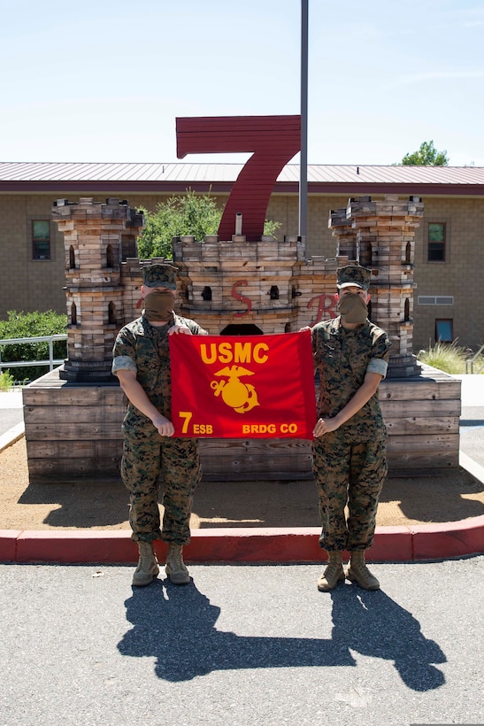 Capt. Micah Tate and GySgt. Valerie Wofford hold the Bridge Company guidon in front of the 7th Engineer Support Battalion (7th ESB), headquarters building on Camp Pendleton, California, June 23, 2020. Bridge Company, 7th ESB, 1st Marine Logistics Group (1st MLG) was deactivated on June 22, on Camp Pendleton, California. Company “C,” 7th ESB, 1st MLG was activated the same day to continue to train to conduct multiple functions of general engineering along with nonstandard gap crossing engineering reconnaissance mission capabilities to enhance the mobility of I Marine Expeditionary Force. (U.S. Marine Corps Photo by Sgt. Maximiliano Rosas)