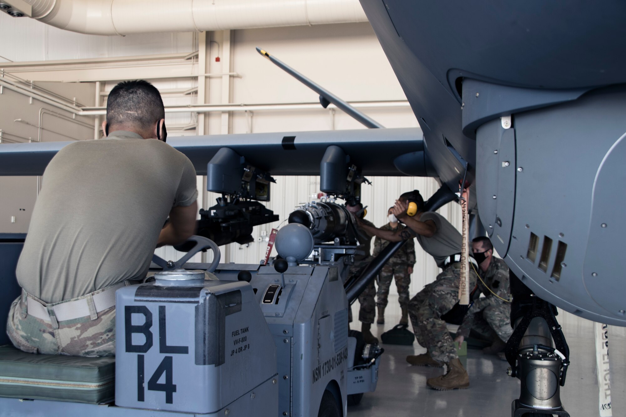 Airmen wearing facemasks compete to arm an MQ-9 Reaper during a quarterly load crew competition.