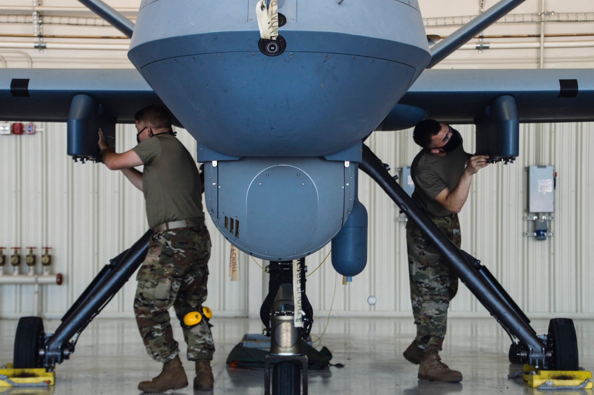 Airmen wearing facemasks compete to arm an MQ-9 Reaper during a quarterly load crew competition.