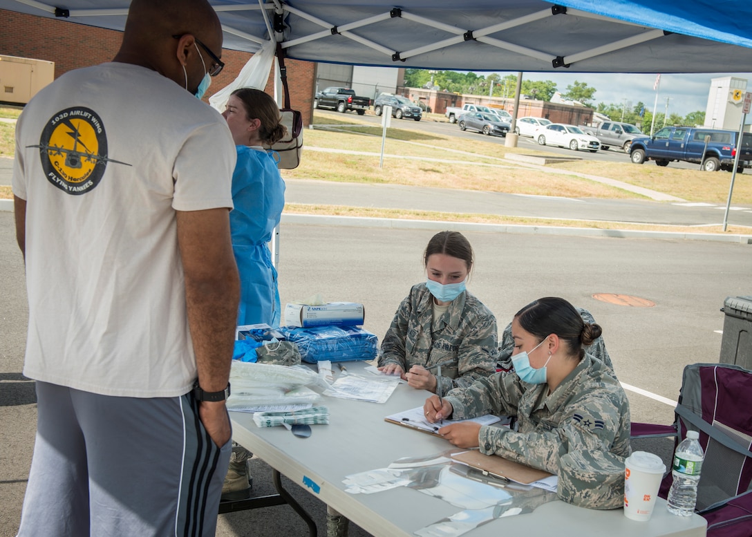 Airman Milena Zuffelato (center) and Airman 1st Class Meilany Caimares, 103rd Medical Group aerospace medical technicians, check in a 103rd Airlift Wing Airman for COVID-19 testing at Bradley Air National Guard Base in East Granby, Connecticut, June 19, 2020. The 103rd Medical Group worked in partnership with the Connecticut National Guard 14th Civil Support Team, New York National Guard 24th Civil Support Team, and Connecticut Department of Public Health to provide COVID-19 testing to Connecticut Air National Guard personnel. (U.S. Air National Guard photo by Staff Sgt. Steven Tucker)