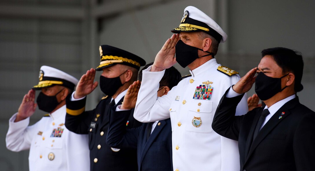 U.S. military and South Korean civilian leaders wearing face masks hold a solemn salute.