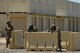A photo of three Air Force Airmen pointing their training weapons up front behind barriers