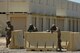 A photo of three Air Force Airmen pointing their training weapons up front behind barriers