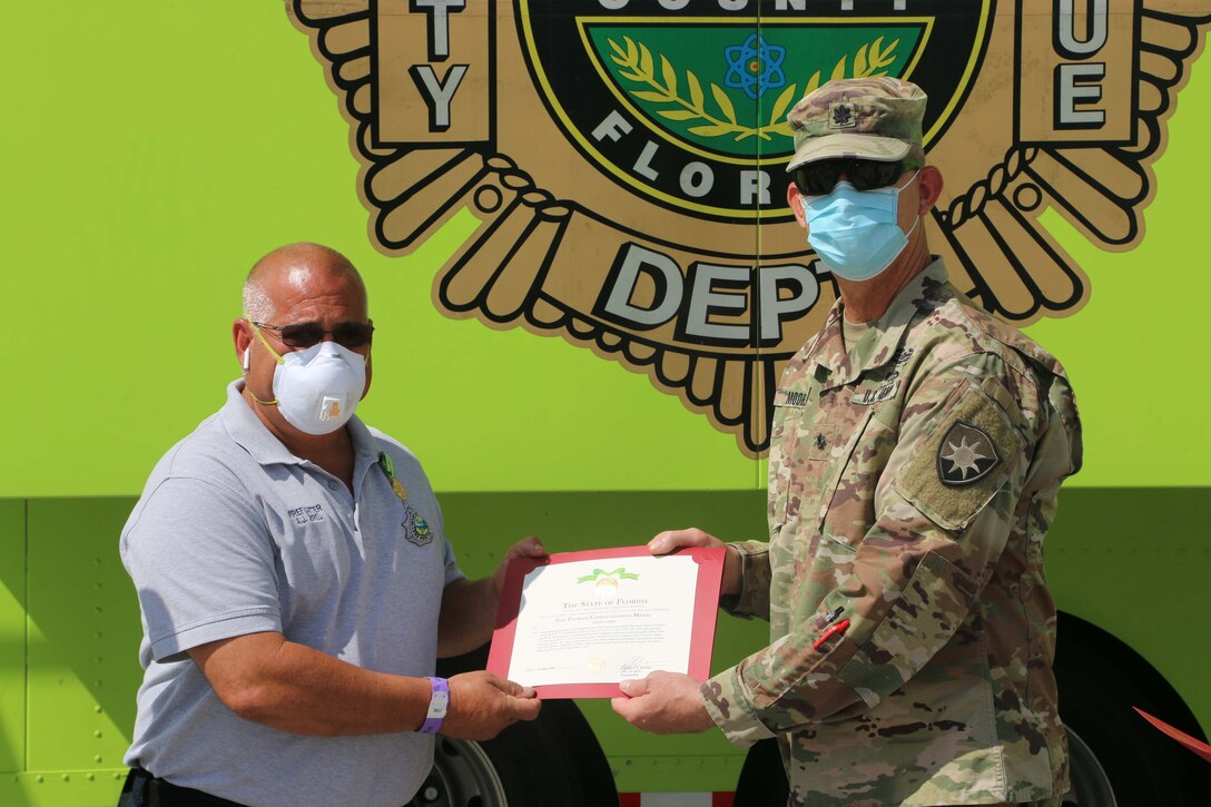 A soldier presents an award to a civilian.