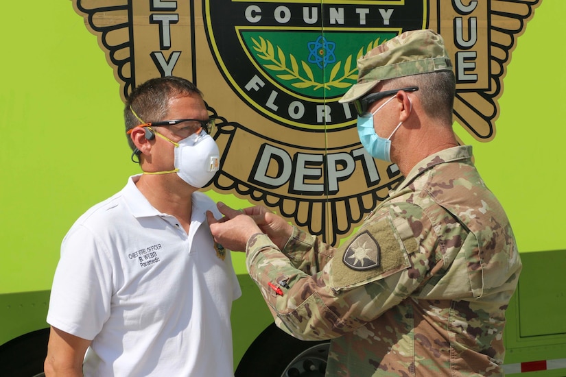 A soldier presents an award to a civilian.