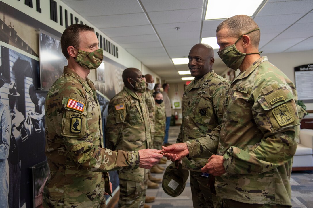 Sergeant Major of the Army gives a coin to a Soldier.