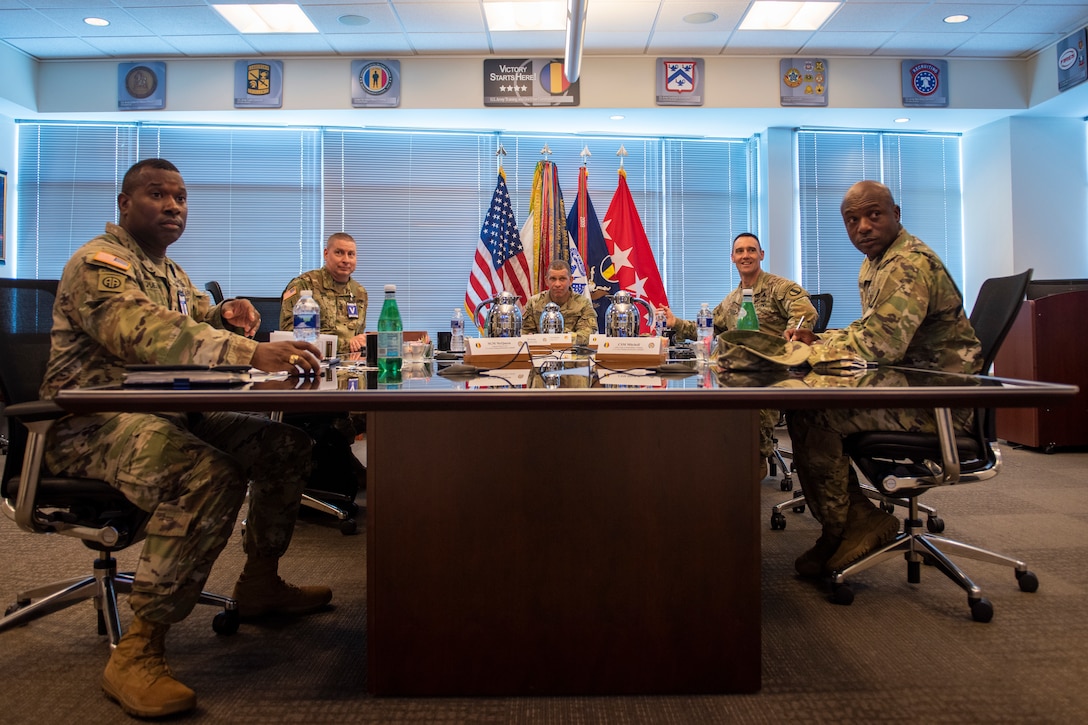 A group of Soldiers sit at a table during a briefing.