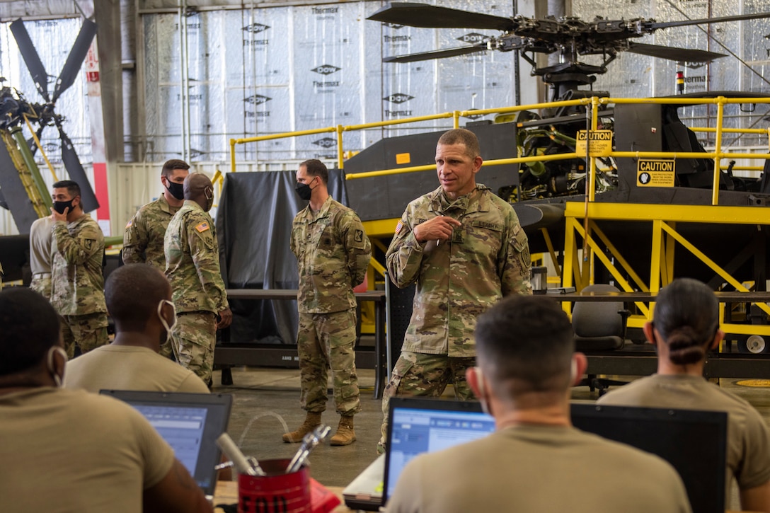 Sergeant Major of the Army talks with a group of Advanced Individual Training students in a helicopter hangar.