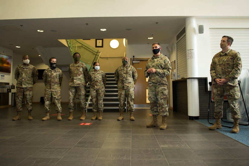 Service members wearing face masks stand during an awards ceremony.