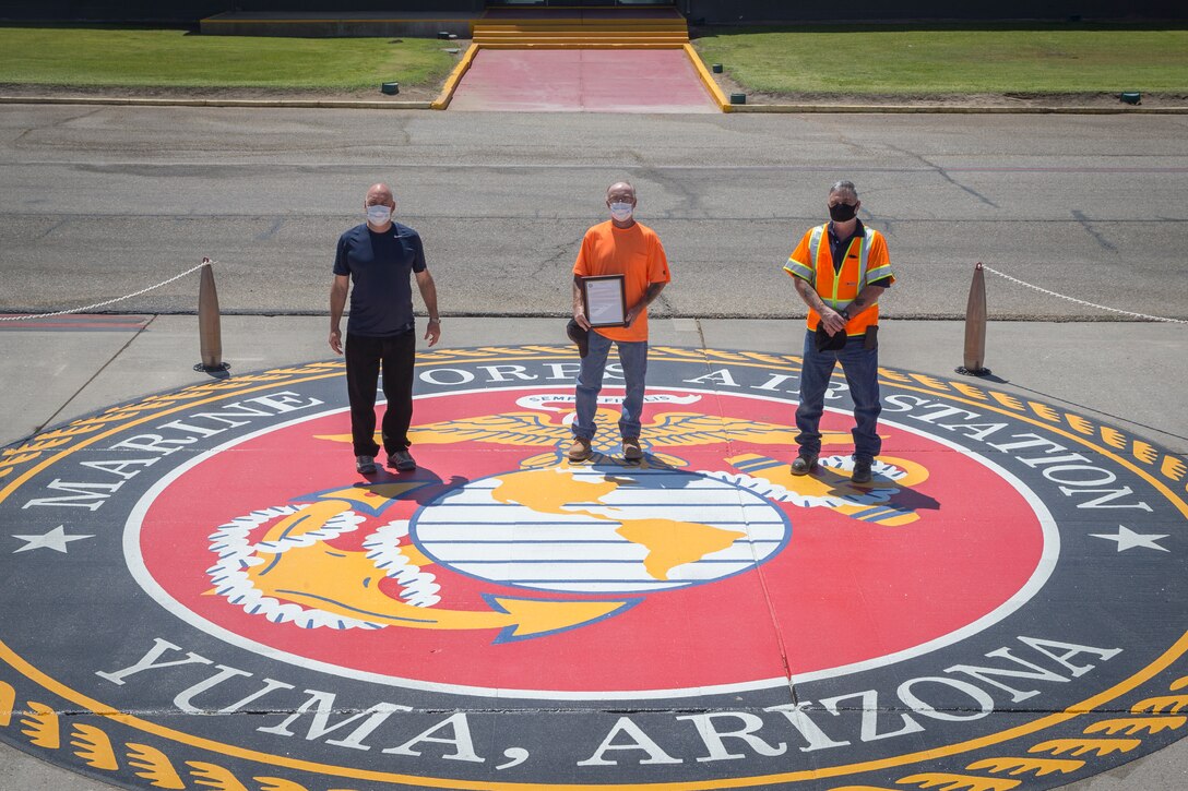 U.S. Marine Corps Col. David A. Suggs, commanding officer, Marine Corps Air Station (MCAS) Yuma, presents civilian contractors with a letter of appreciation (LOA) for their work on MCAS Yuma, at the MCAS Yuma base operations building, June 11, 2020. The LOA was presented for the new Marine Corps Emblem constructed on the visiting aircraft line apron. (U.S. Marine Corps photo by Lance Cpl John Hall)