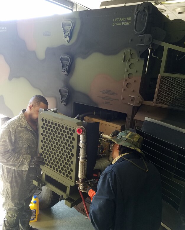 Photo of Field Service Representatives Edward Smith, left, and William Jason servicing generators and environmental control units