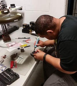 Photo of Electronics Engineer Clinton William repairing printed circuit boards for the Army’s PRC-148 Multiband Inter/Intra Team Radio