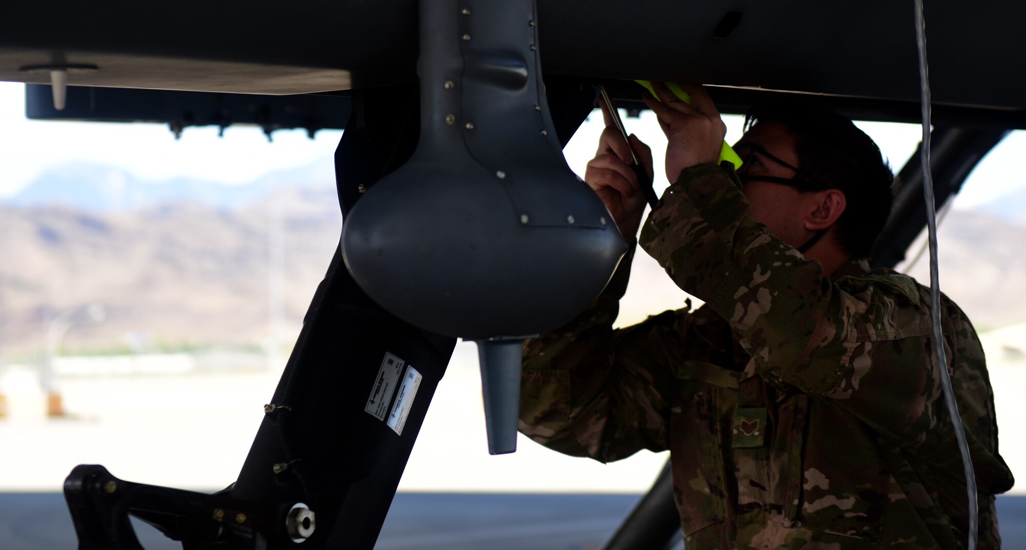 Staff Sgt. Hunter, 432nd Aircraft Maintenance Squadron crew chief, inspects the underbody of an MQ-9 Reaper.