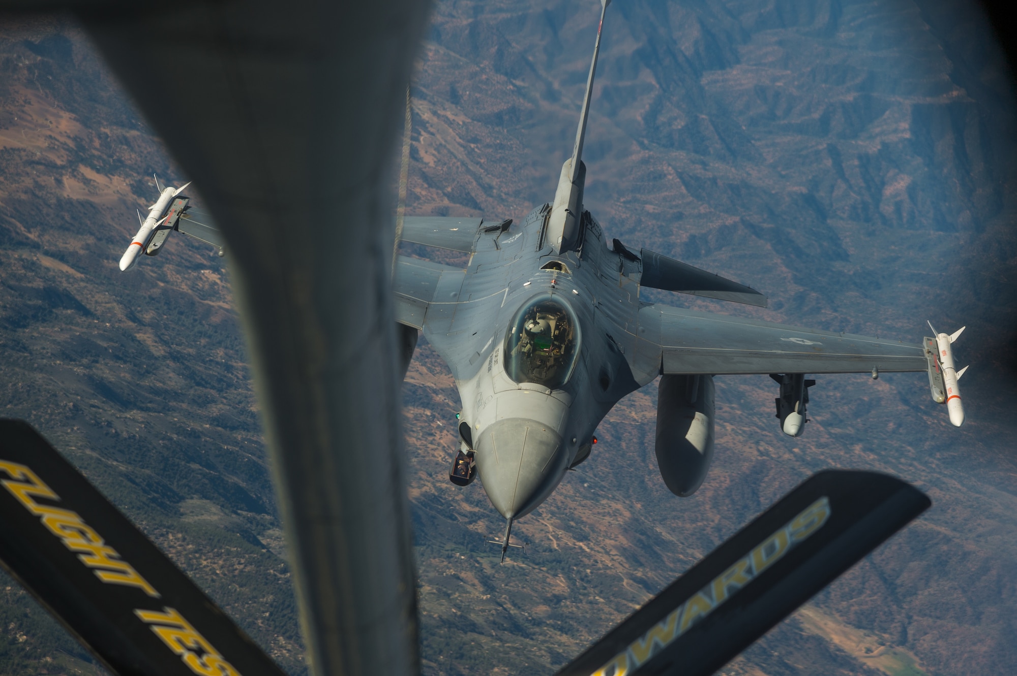 An F-16 Fighting Falcon flown by Maj. Jacob Schonig from the 416th Flight Test Squadron at Edwards Air Force Base, California, conducts a mid-air refueling operation with a KC-135 Stratotanker during a captive-carry flight test of a Gray Wolf cruise missile prototype, June 9. (Air Force photo by Ethan Wagner)