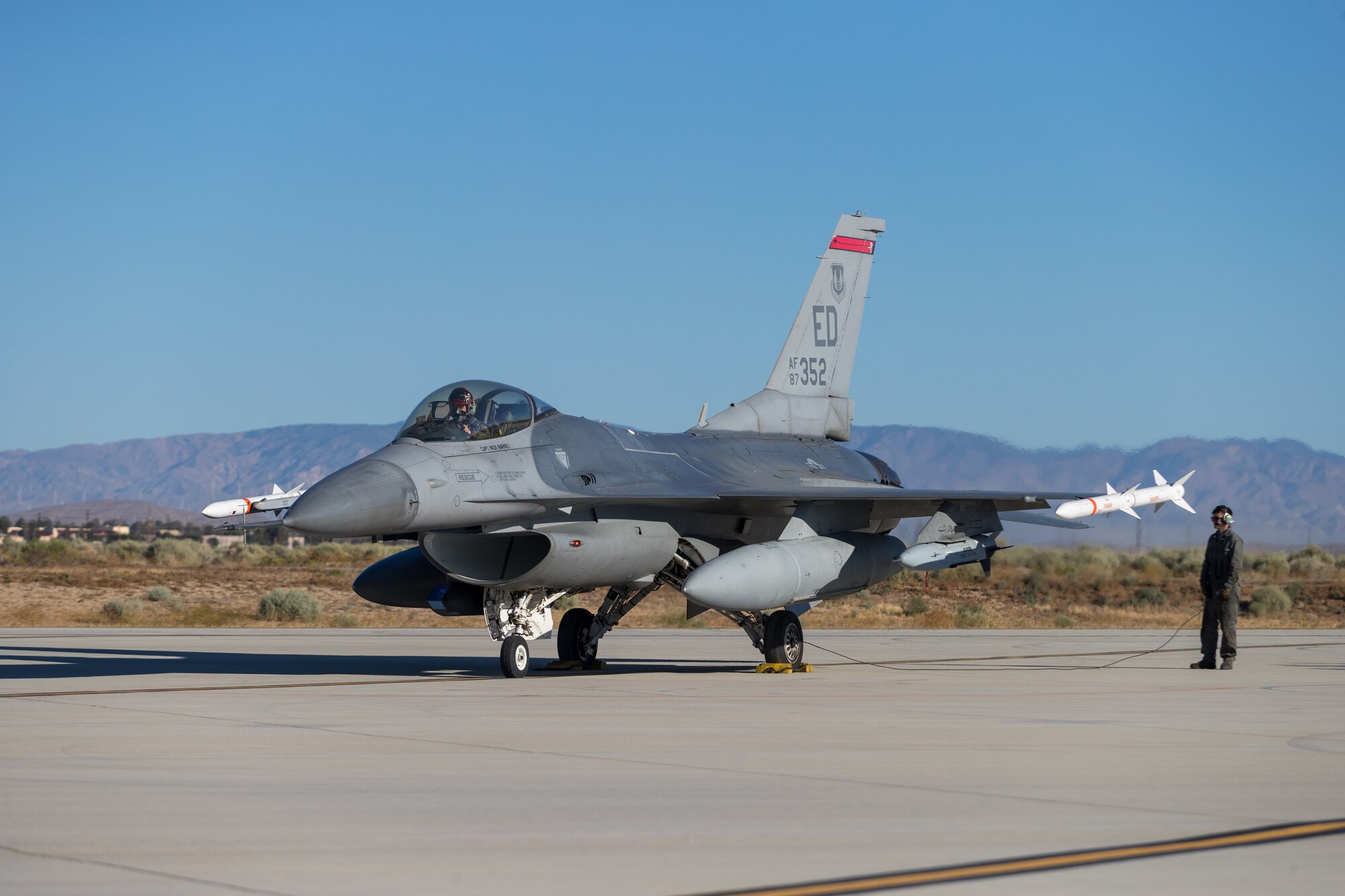 F-16 Fighting Falcon crew chief, Airman 1st Class Wyatt Hegner, prepares Maj. Jacob Schonig, 416th Flight Test Squadron, for a captive-carry flight test of the Gray Wolf cruise missile prototype at Edwards Air Force Base, California, June 9. (Air Force photo by Kyle Brazier)