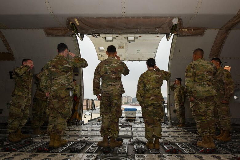 Airmen salute a transfer case during a repatriation