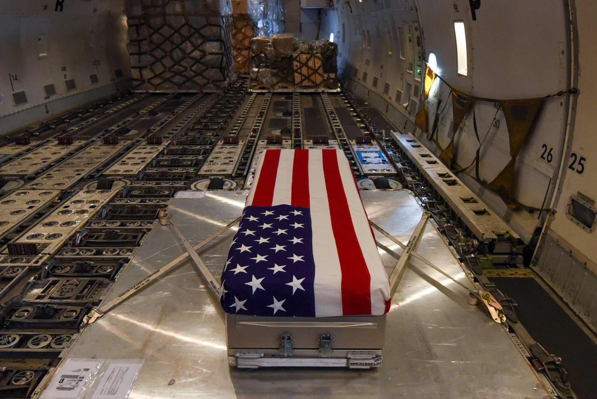 An American Flag is draped over a transfer case on aircraft