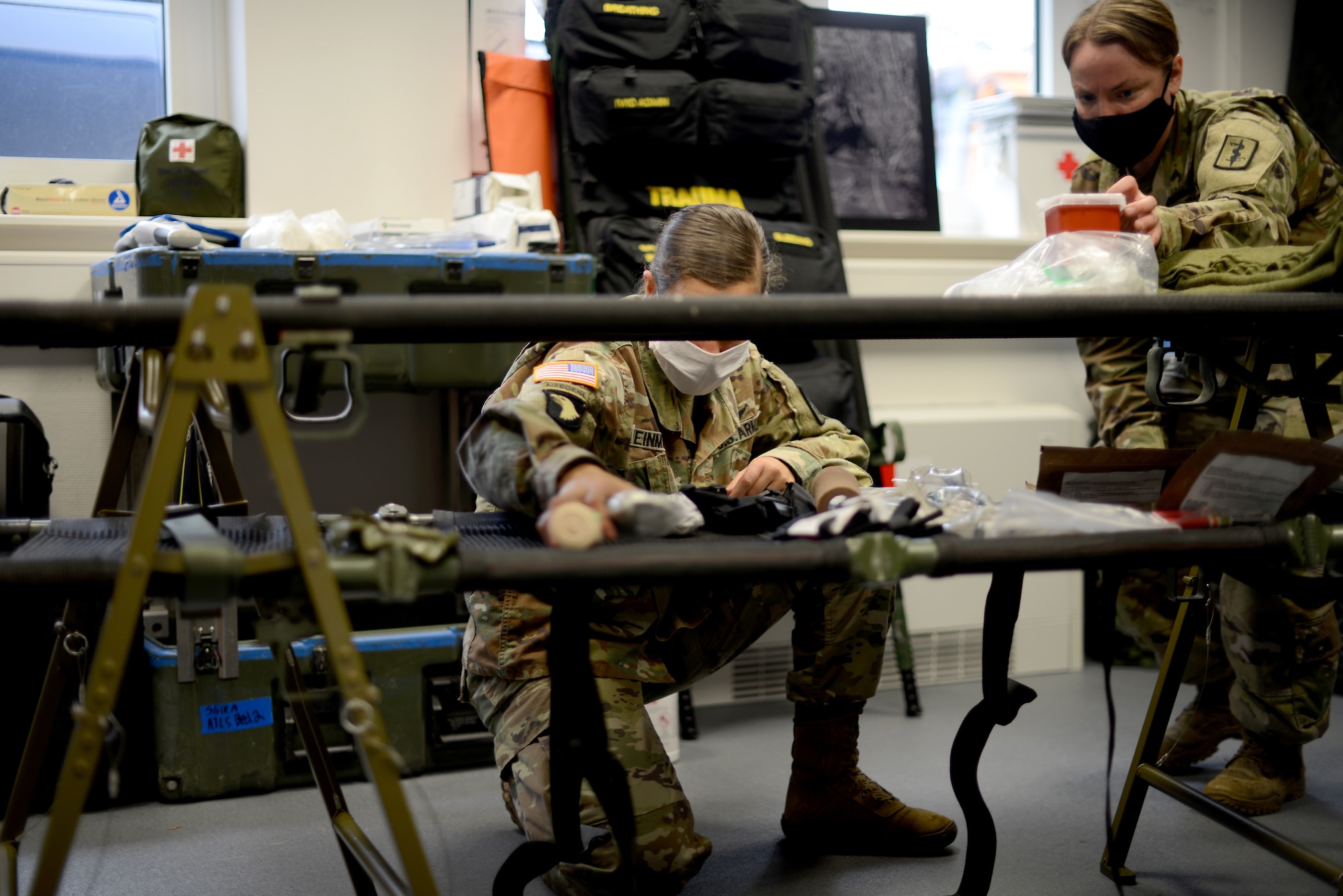 U.S. Army Capt. Jessica Weinman, 67th Forward Resuscitative Surgical Team emergency nurse, center, and Sgt. Sara Lind, 67th FRST combat medic, right, set up the resuscitation section for patient care prior to a training scenario at the Medical Simulation Training Center, Ramstein Air Base, June 18, 2020.