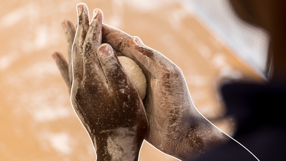 one person's hands covered in flour forming a dough ball.