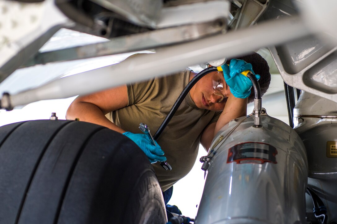 Hydraulics technician attaches a hose to the landing gear of a C17