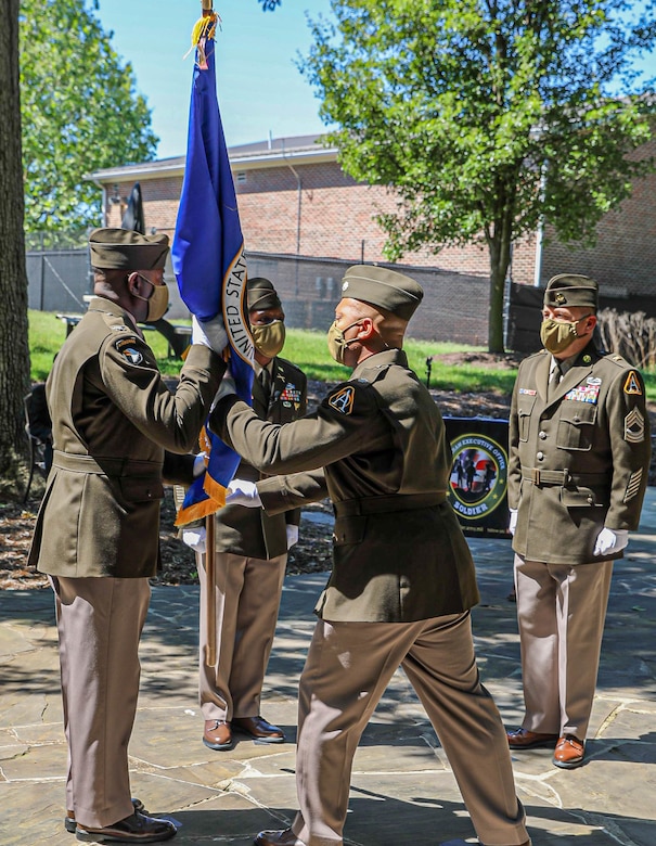 Lt. Col. Jonathan Allen passes the Army Acquisition Corps flag to Col. Stephen Thomas, signifying the relinquishing of his Product Management responsibilities during the PdM SCIE change of charter on Fort Belvoir, Virginia, June 12, 2020.