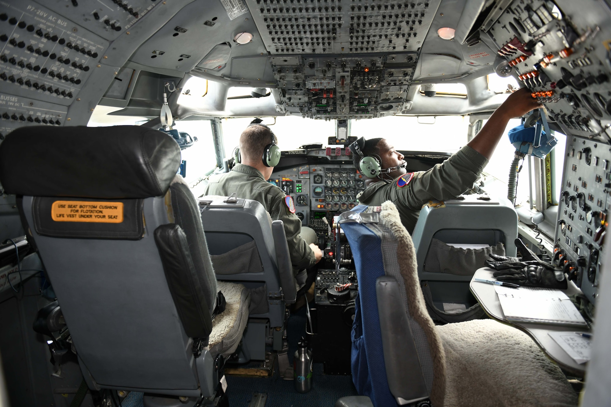 Photo shows two Airmen in the cockpit of an aircraft.