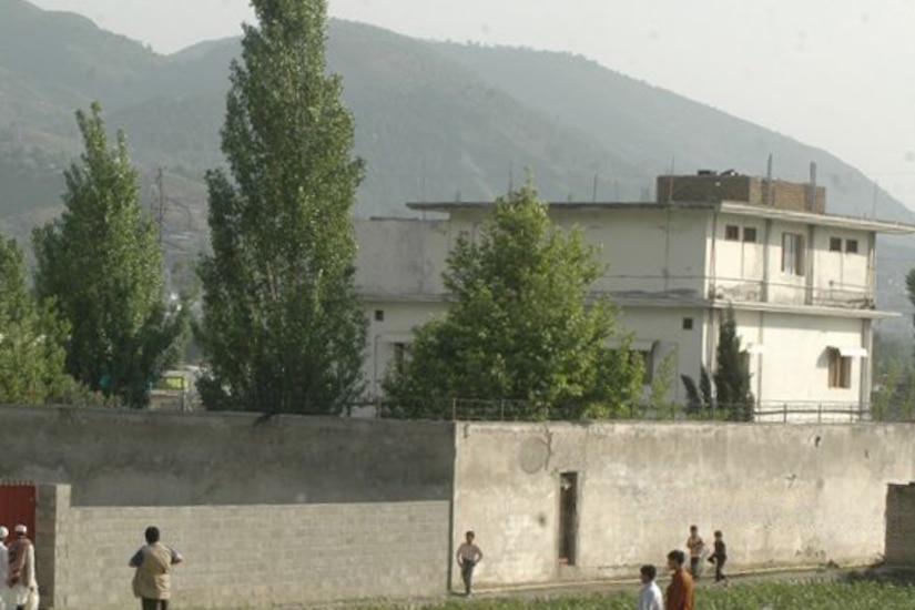 People approach a wall surrounding a compound.