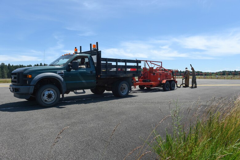 Pavement and construction technicians from the 627th Civil Engineer Squadron work together to reseal cracks on the McChord Field flight line on Joint Base Lewis-McChord, Wash., June 25, 2020. Resealing is done with melted tar funneled into the cracks and left to dry, which prolongs the life of the flight line by preventing erosion. (U.S. Air Force photo by Airman 1st Class Mikayla Heineck)