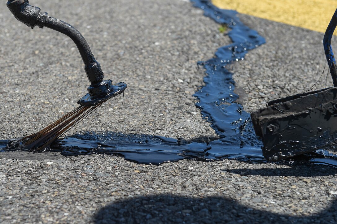 Melted tar is funneled into cracks on the McChord Field flight line on Joint Base Lewis-McChord, Wash., June 25, 2020. Resealing cracks on the flight line prolongs its life and is quicker and less expensive in the short term than replacing whole sections of asphalt. (U.S. Air Force photo by Airman 1st Class Mikayla Heineck)