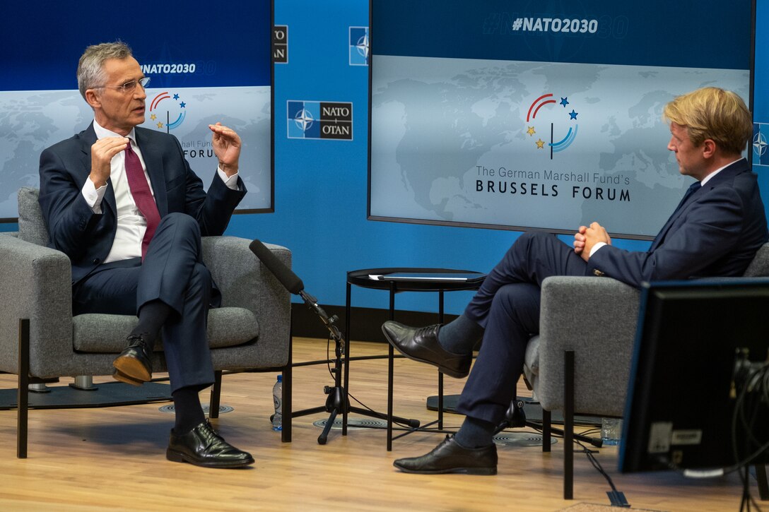 Two men speak together on camera at a television studio.