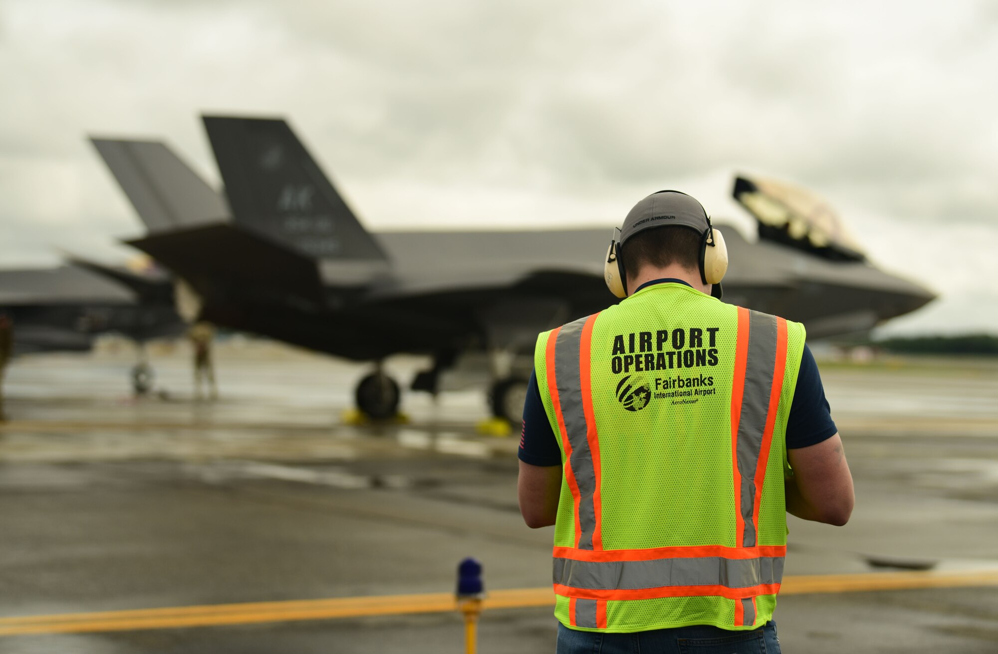 A Fairbanks International Airport employee waits as Airmen from the 356th Aircraft Maintenance Unit recover an F-35A Lightning II after landing, June 24, 2020.