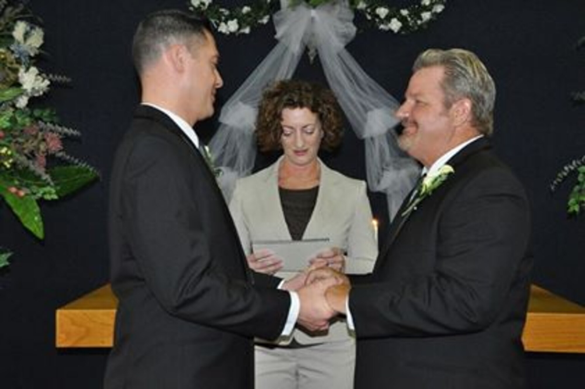 Marvin Tucker, emergency manager, 452nd Air Mobility Wing (right), and his new husband, Joshua Delgado, exchange vows Aug. 3, 2013, in the historic March Air Reserve Base chapel surrounded by family and friends, including officiant, Maj. Tina Tsui, 452nd Force Support Squadron commander.