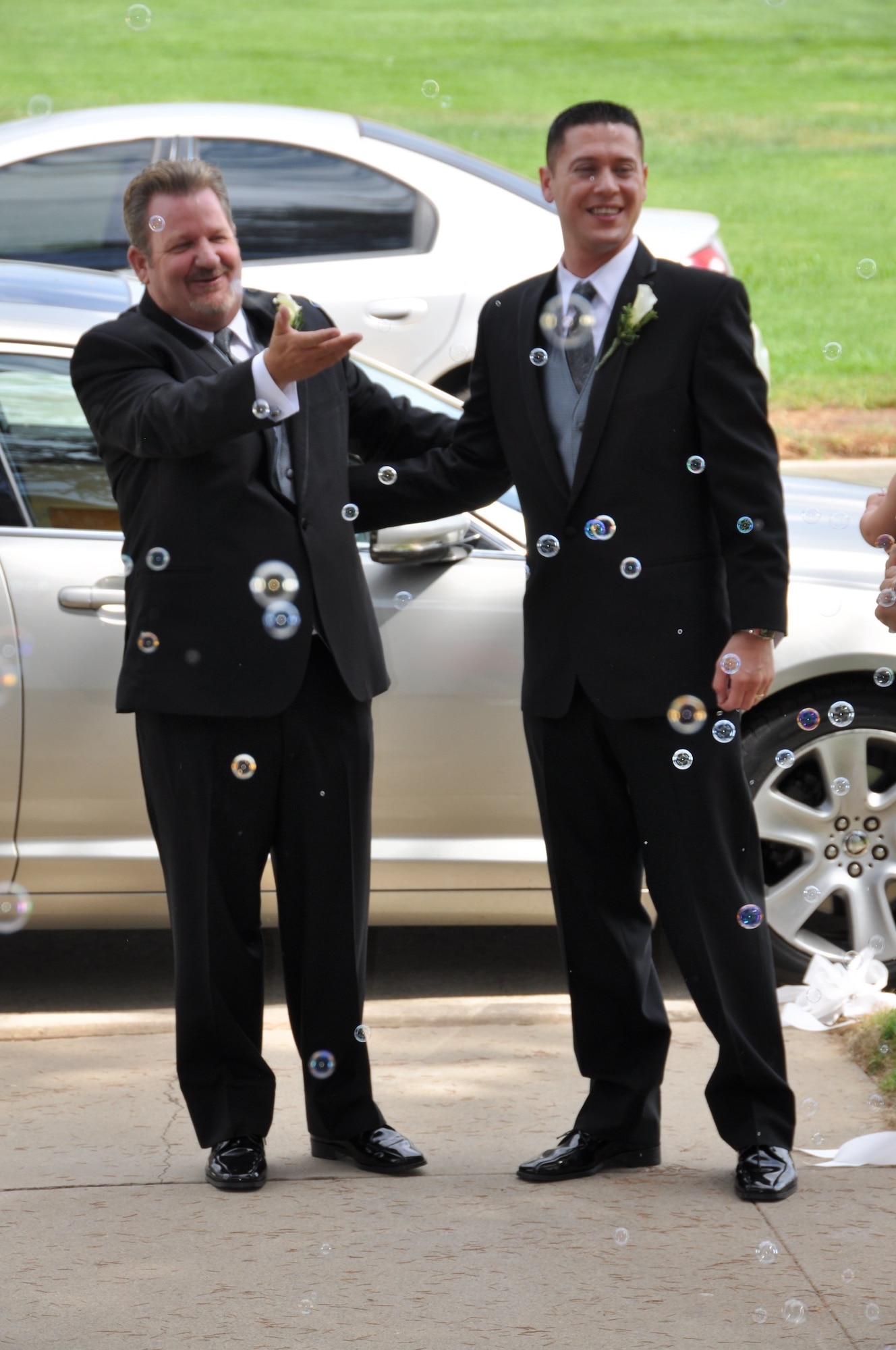 Marvin Tucker, emergency manager, 452nd Air Mobility Wing (left), and his new husband, Joshua Delgado, stop outside the historic March Air Reserve Base chapel, Aug. 3, 2013, to respond to the cheering guests after the couple became the first same-sex couple to be married at March ARB.