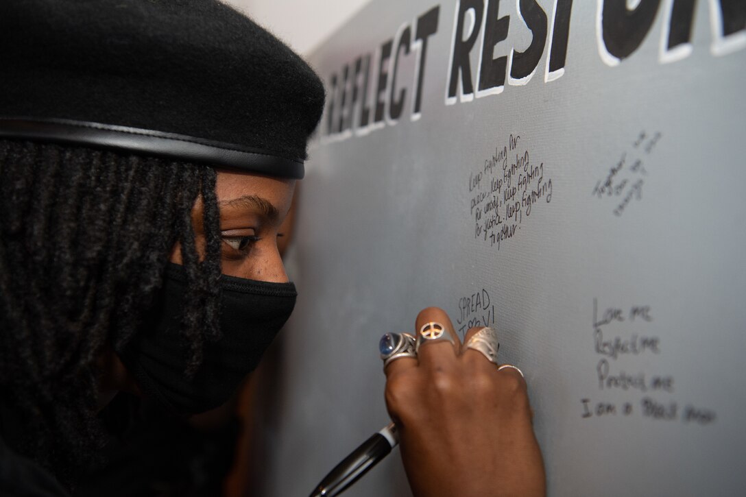 U.S. Air Force Tech Sgt. Johne Tribble, 86th Airlift Wing legal office noncommissioned officer in charge of litigation, writes on a message board titled, “Listen, Reflect, Respond,” during the Juneteenth: Vigil for Healing event at Ramstein Air Base, Germany, June 19, 2020.