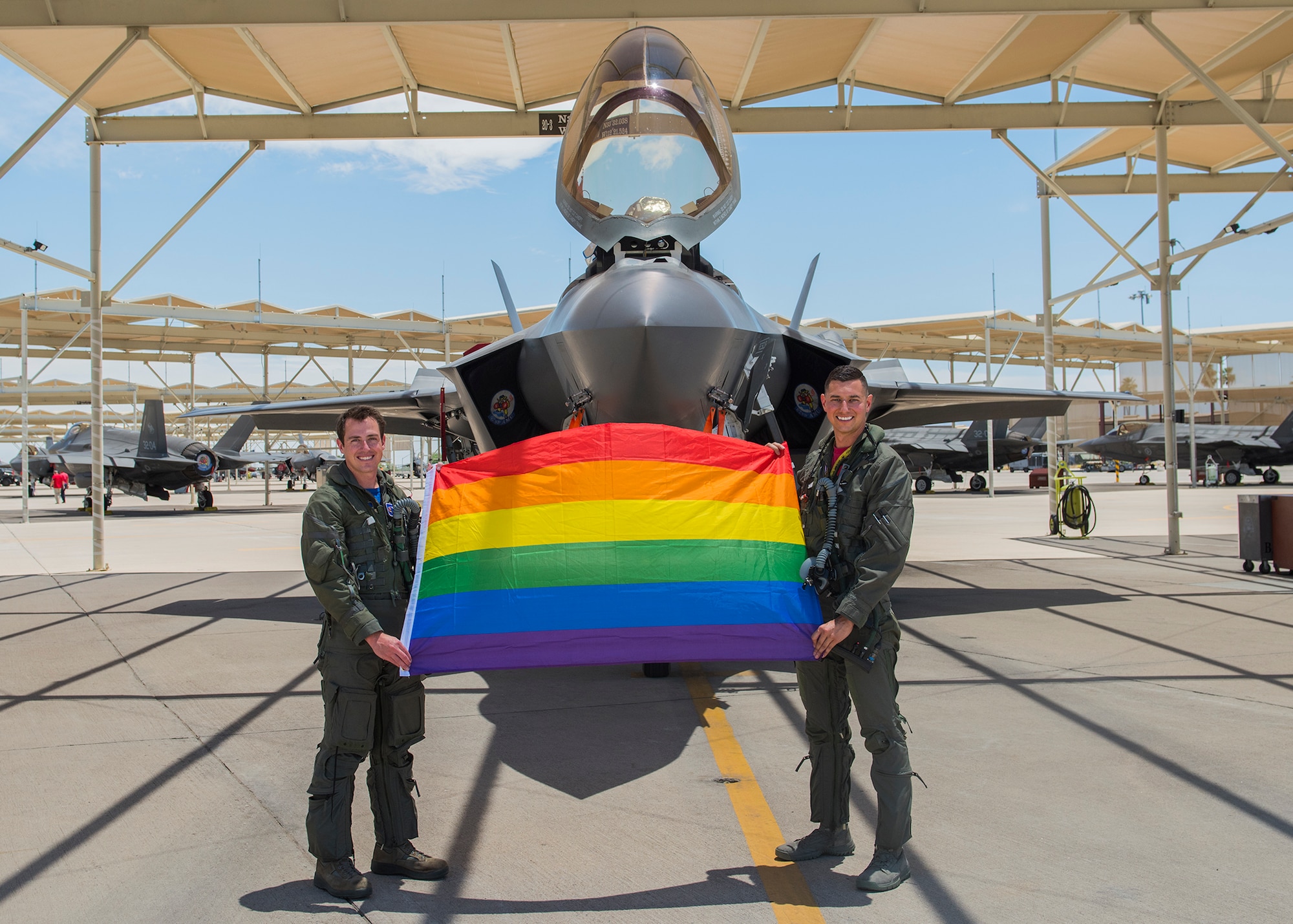 Maj. Tyler McBride, 62nd Fighter Squadron F-35A Lightning II instructor pilot, and Capt. Justin Lennon, 56th Training Squadron F-35 instructor pilot, hold an LGBTQ+ Pride flag after a Pride Month flyby June 26, 2020, at Luke Air Force Base, Ariz.