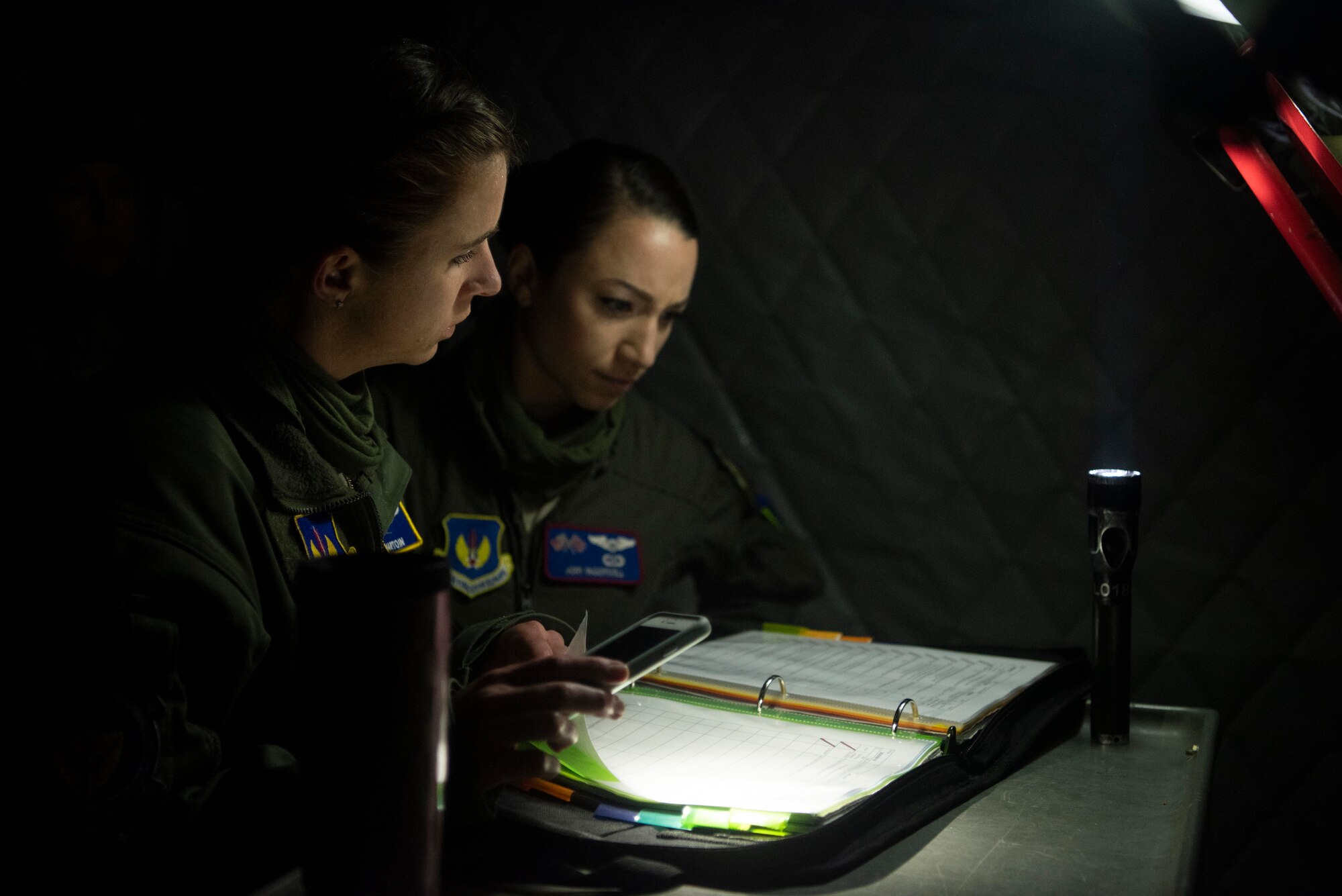 Capt. Marissa Hartoin, 100th Operations Support Squadron chief of wing tactics and instructor pilot, left, and Capt. Jori Ingersoll, 351st Air Refueling Squadron pilot, review KC-135 Stratotanker maintenance records before supporting a strategic bomber mission at RAF Mildenhall, England, June 18, 2020. The 100th Air Refueling Wing provides rapid aerial refueling throughout the U.S. Air Forces in Europe and Air Forces Africa theater. (U.S. Air Force photo by Airman 1st Class Joseph Barron)