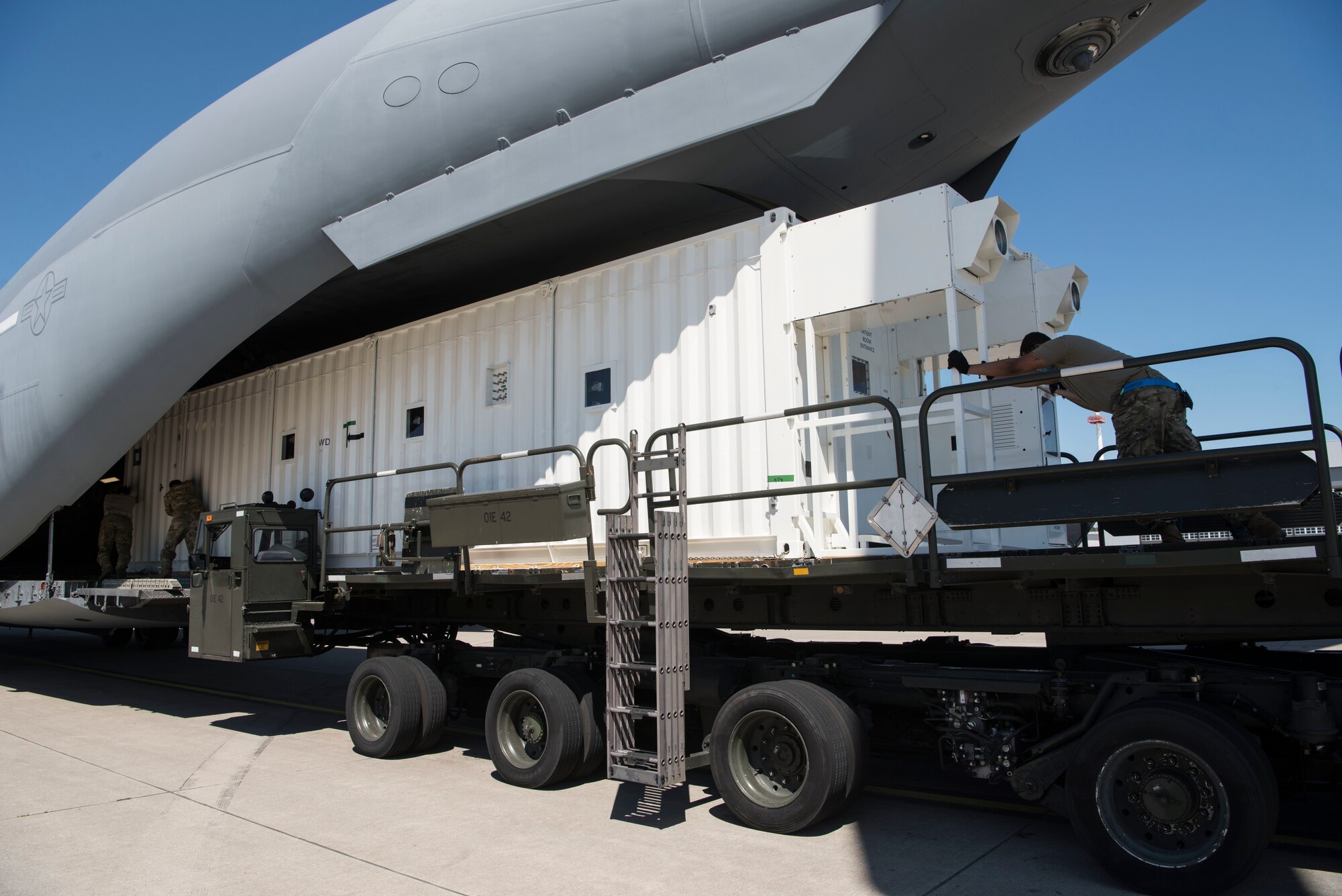 U.S. Air Force personnel assigned to the 721st Aerial Port Squadron push a Negatively Pressured Conex onto a C-17 Globemaster III aircraft