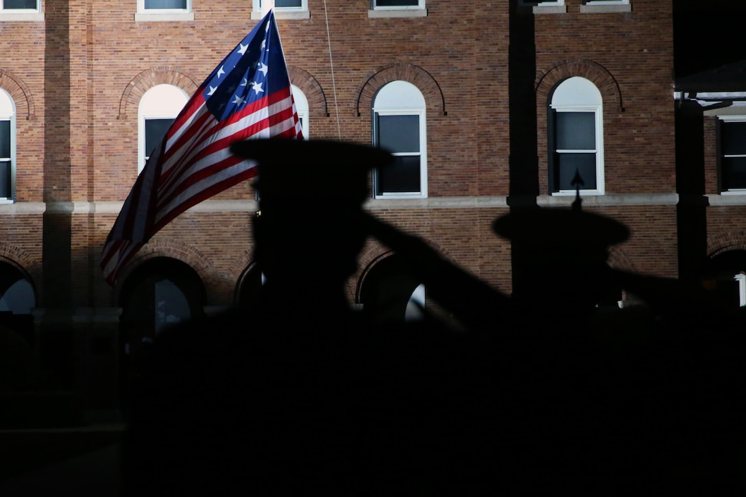 Marines execute a hand salute while observing evening colors during the Friday Evening Parade at Marine Barracks Washington, D.C., June 26, 2020. This parade season, the Barracks adapted aspects of the ceremony to maximize safety precautions and to follow Department of Defense guidelines and Centers for Disease Control and Prevention (CDC) recommendations. The hosting official for the evening was Col. Teague A. Pastel, commanding officer, Marine Barracks Washington, and the 38th Commandant of the Marine Corps, Gen. David H. Berger, was the guest of honor. (U.S. Marine Corps photo by Lance Cpl. Allen Sanders)