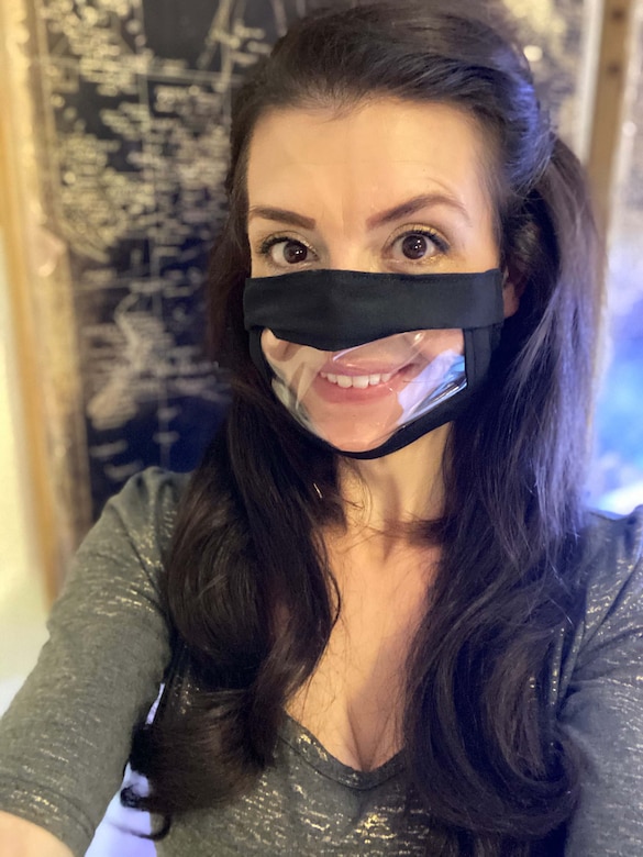 A woman wears a face mask with a window over the mouth.