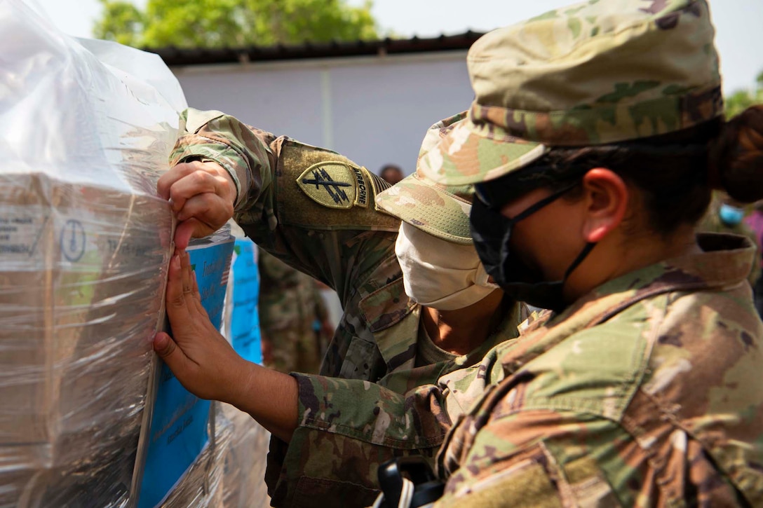 Two soldiers wearing masks label boxes.