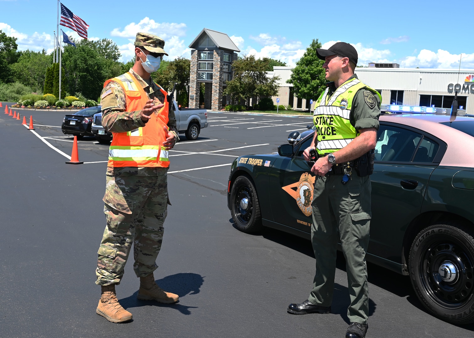 Spc. Ryan Stone, 197th Field Artillery Brigade, New Hampshire Army National Guard, and Trooper Doug Bailey of Troop B, New Hampshire State Police, work a traffic post at a mobile food pantry conducted on June 26 in Manchester.