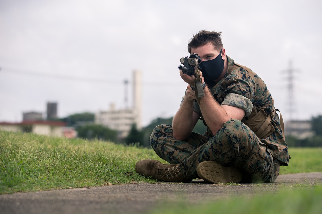 A seated Marine practices marksmanship fundamentals.