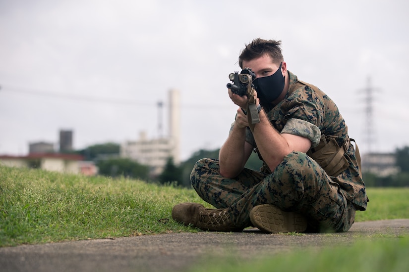 A seated Marine practices marksmanship fundamentals.