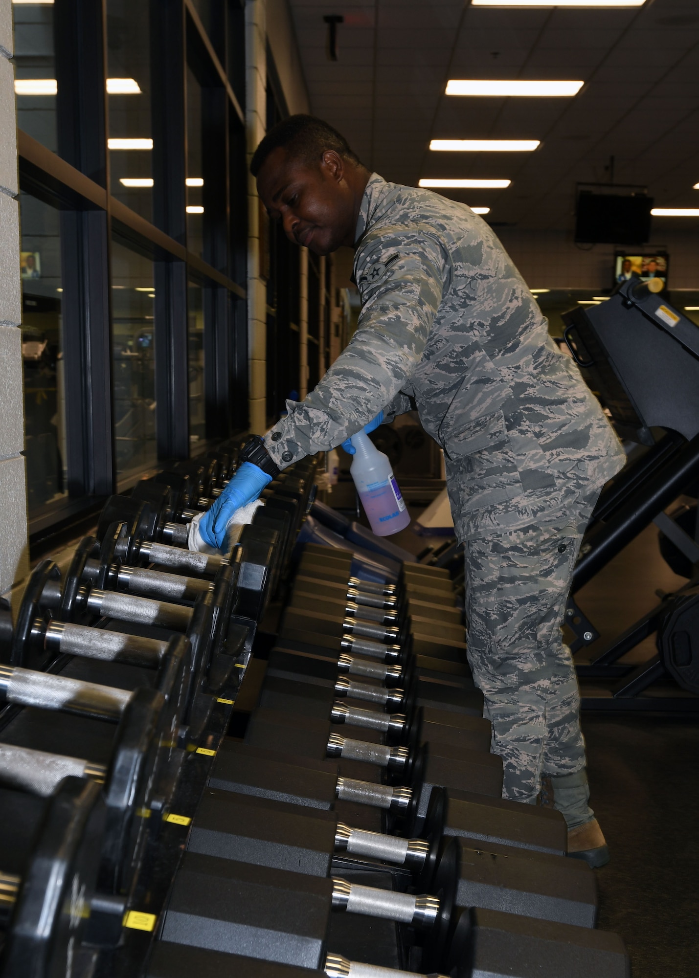 Airman Moise Azuma, 22nd Force Support Squadron fitness and sports apprentice, sanitizes dumbbells June 19, 2020, at McConnell Air Force Base, Kansas. The staff cleans the facility thoroughly twice a day, without customers present as an extra sanitation measure to keep everyone healthy who works and uses the gym. (U.S. Air Force photo by Tech. Sgt. Jennifer Stai)