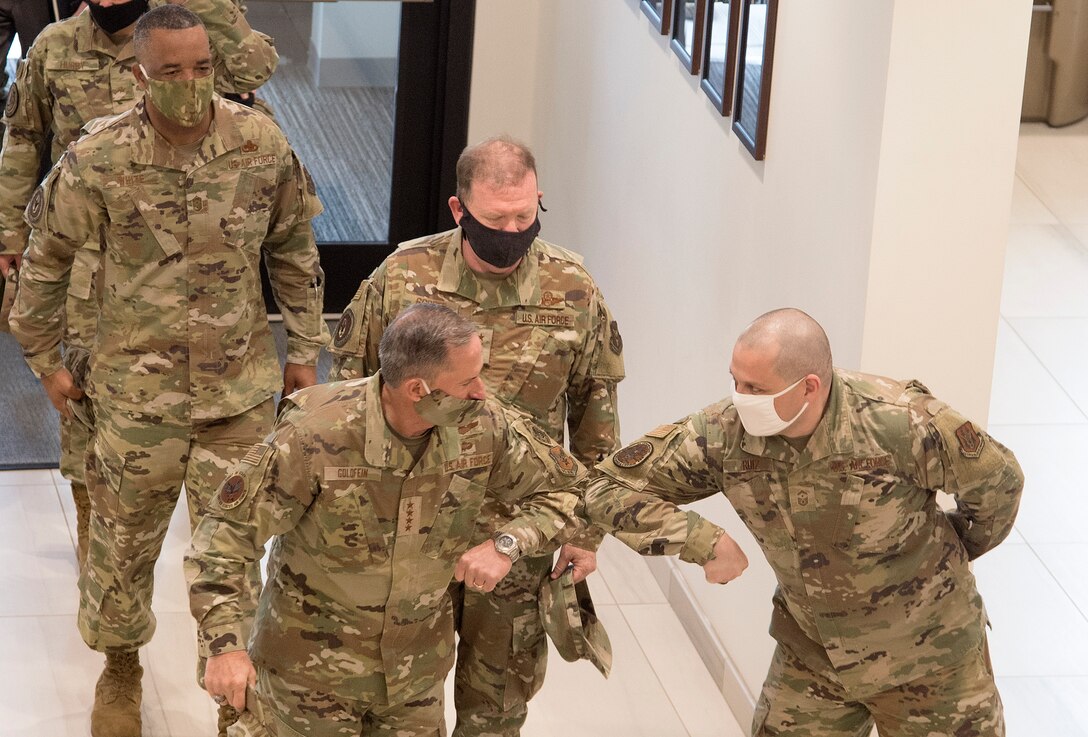 Photo of Air Force Chief of Staff Gen. David L. Goldfein greeting Air Force Reserve Command First Sergeant Senior Master Sgt. Orlando Ruiz, with an elbow bump as a safety measure against COVID-19, while Command Chief Master Sergeant of AFRC Timothy C. White Jr., back left, and Chief of Air Force Reserve Lt. Gen. Richard W. Scobee, looks on, at Robins Air Force Base, Georgia, June 24, 2020.