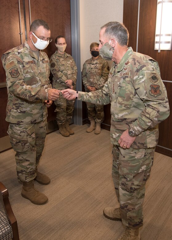Photo of Air Force Chief of Staff Gen. David L. Goldfein, giving a coin to Master Sgt. Robert Crowe, a Branch Superintendent for A6 in Air Force Reserve Command, for his contributions in boosting teleworking capabilities during the COVID-19 pandemic at Robins Air Force Base, Georgia, June 24, 2020.